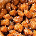 Close-up of glazed chicken pieces sprinkled with sesame seeds.