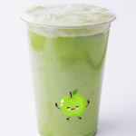 A clear plastic cup filled with a frothy green smoothie featuring a cute, smiling cartoon apple on the side.