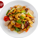 A dish of stir-fried vegetables and nuts on a white plate, featuring bell peppers, mushrooms, carrots, cashews, and garnished with cilantro.