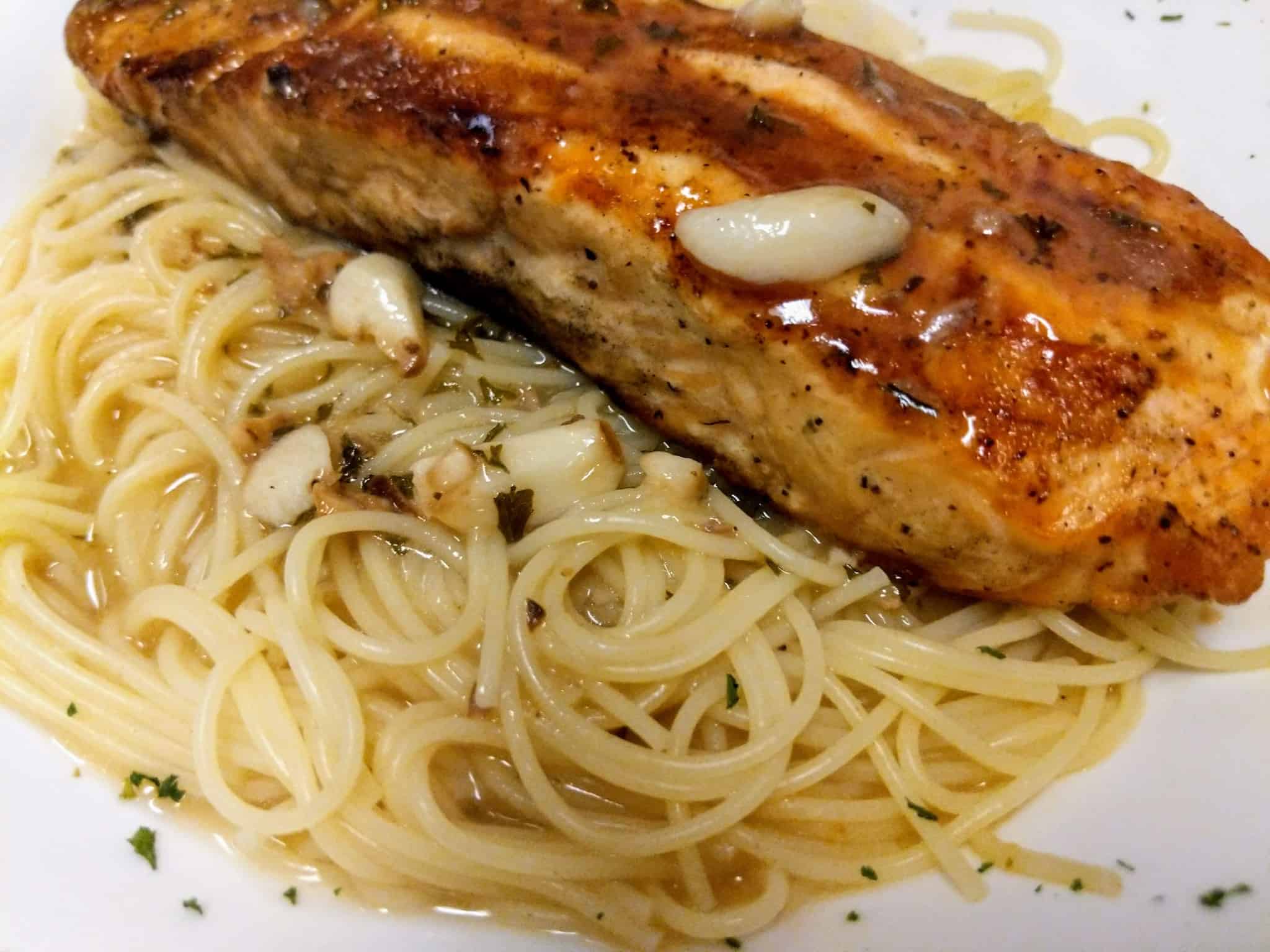 A plate of salmon and spaghetti on a white plate.