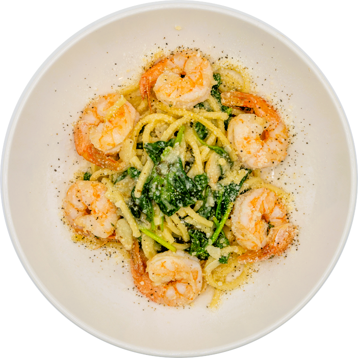 A bowl of pasta with shrimp, spinach, and grated cheese, garnished with ground black pepper.