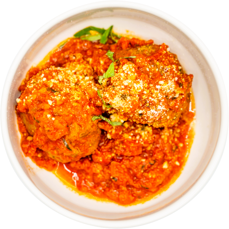 A bowl containing two meatballs covered in tomato sauce, garnished with grated cheese and chopped herbs.