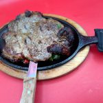 A steak in a skillet with a fork.