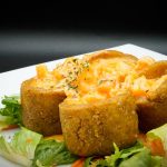 A white plate with a stuffed potato with salad on it.