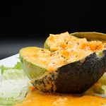 A stuffed avocado on a white plate.