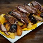 A plate of meat and vegetables on a wooden table.