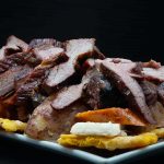 A plate of meat and potatoes on a black background.