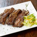 Ribs with salad on a white plate.